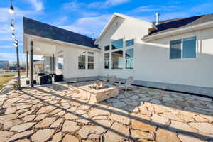 Back of property with a patio area, a fire pit, roof with shingles, and stucco siding