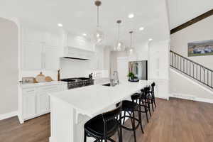 Kitchen featuring a kitchen bar, an island with sink, white cabinets, dark wood finished floors, and stainless steel appliances