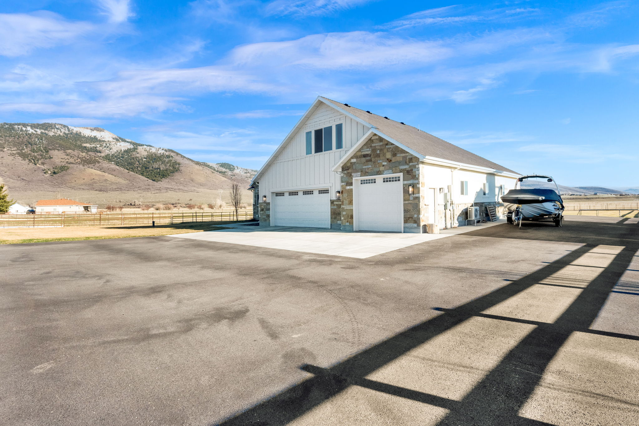 View of side of property with stone siding, a mountain view, driveway, and board and batten siding