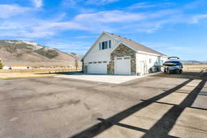 View of side of property with stone siding, a mountain view, driveway, and board and batten siding
