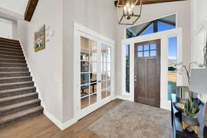 Entryway featuring vaulted ceiling, light wood-style flooring, french doors, and suspended lighting