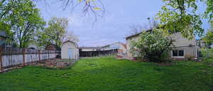Fenced backyard featuring a shed