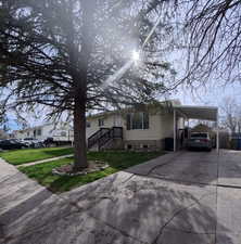 View of front of property featuring an attached carport, a front yard, and concrete driveway
