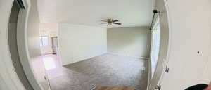 Unfurnished room with a ceiling fan, healthy amount of natural light, and light carpet