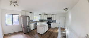 Kitchen featuring stainless steel appliances, dark wood-style flooring, and white cabinetry
