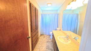 Bathroom with vanity, curtained shower, and a closet