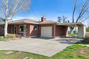Ranch-style house with an attached garage, concrete driveway, a chimney, and an attached carport