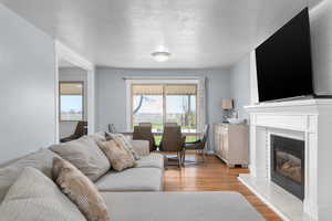 Living area with light wood-style flooring, a textured ceiling, and a glass covered fireplace