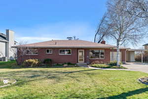 Ranch-style house featuring a front yard, brick siding, and driveway