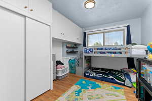 Bedroom featuring light wood-style flooring, a textured ceiling, and a closet