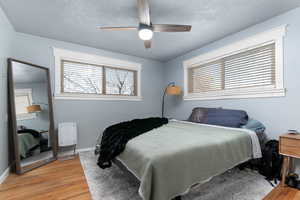 Bedroom with light wood-style floors, a ceiling fan, and a textured ceiling