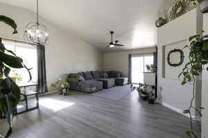 Living area with vaulted ceiling, light wood-style flooring, a ceiling fan, and hanging lights