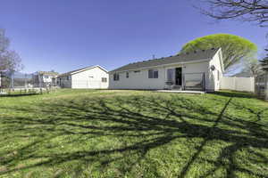 Rear view of house with a trampoline, a patio, and a fenced backyard