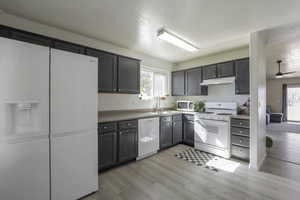 Kitchen with white appliances, light countertops, light wood-style floors, and a ceiling fan