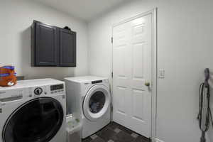 Laundry area with cabinet space, independent washer and dryer, and stone finish flooring
