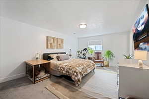 Bedroom with light carpet and a textured ceiling