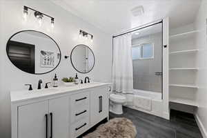 Bathroom featuring double vanity and shower / tub combo with curtain