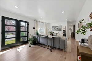 Living area featuring french doors, arched walkways, light wood-style flooring, and recessed lighting