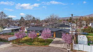 View of front of property with a residential view, a fenced front yard, driveway, a garage, and a mountain view