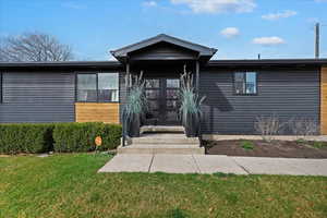 View of front of house with french doors and a front lawn