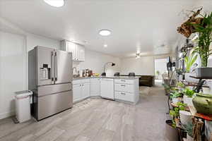 Kitchen with high end fridge, a peninsula, open floor plan, white cabinetry, and white dishwasher