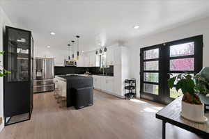 Kitchen featuring stainless steel appliances, a kitchen breakfast bar, white cabinetry, and a kitchen island