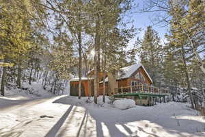 Snow covered rear of property featuring a wooden deck and an outbuilding