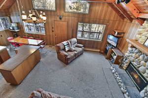 Carpeted living room with wooden ceiling, vaulted ceiling with beams, healthy amount of natural light, wood walls, and a baseboard radiator