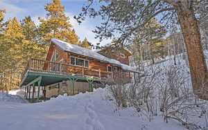 Snow covered property featuring a deck and log veneer siding