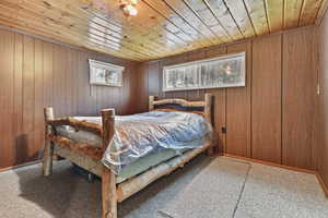 Bedroom featuring wood ceiling, carpet flooring, and wooden walls