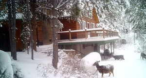 Snow covered property with a wooden deck and a patio