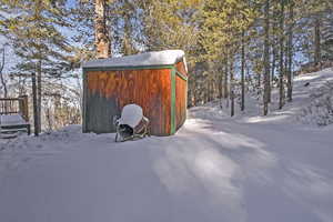Snow covered structure featuring a storage shed