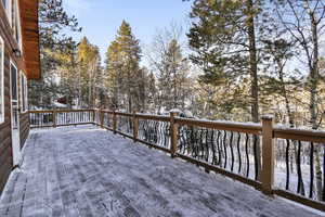 Snow covered deck featuring view of scattered trees