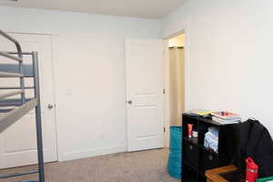 Bedroom featuring light carpet and baseboards