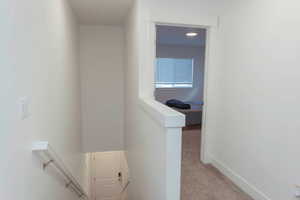 Hallway with light carpet and an upstairs landing