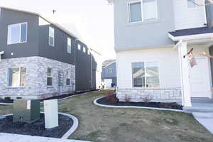 View of front & side of property featuring stone siding, stucco siding, and a lawn