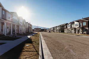 View of asphalt street featuring a residential view, sidewalks, a mountain view, and curbs