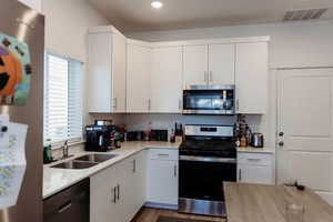 Kitchen featuring stainless steel appliances, light quartz countertops, wood-style floors, white cabinets and recessed lighting