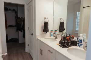 Full master bath with double vanity, a walk in closet, and light wood-type flooring