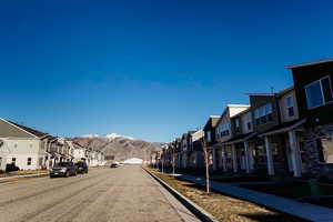 View of asphalt road with a residential view, sidewalks, a mountain view, and curbs