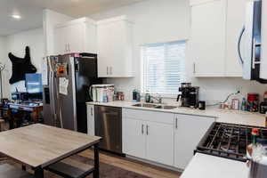 Kitchen with white cabinets, stainless steel appliances, light wood finished floors, and light quartz counters