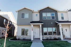 View of front facade (end unit) featuring board and batten siding, stone siding, and a front yard
