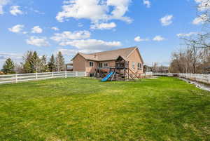Back of property featuring a playground and a fenced backyard