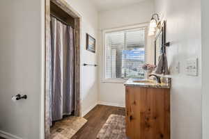 Bathroom featuring a shower with shower curtain, vanity, and dark wood finished floors