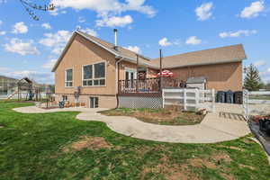 Rear view of house with stucco siding, a deck, a patio, and a playground