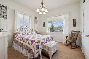 Carpeted bedroom with a chandelier and multiple windows