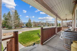 Covered porch featuring a lawn, a mountain view, and a residential view