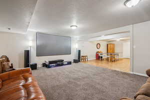 Cinema room featuring a textured ceiling and light carpet