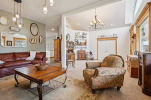 Living room featuring suspended lighting, lofted ceiling, light carpet, and plenty of natural light