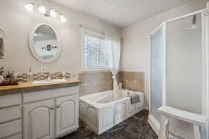 Full bathroom featuring vanity, a whirlpool tub, a shower stall, and dark marble finish floors